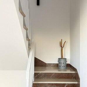 Eine moderne Treppe mit minimalistischem Design, inklusive Metallhandlauf und einem Topf mit einem Kaktus auf der Zwischenebene.