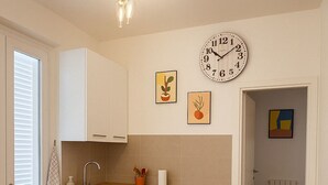 A compact kitchen with white cabinets, a sink, and a dining area with a table and chairs. - Detached house in the center of Tonfano • 100 m from the sea • 2 parking spaces (Marina di Pietrasanta)