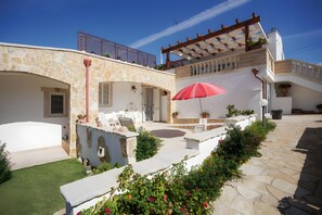 A stone building with a patio, outdoor furniture, and potted plants.