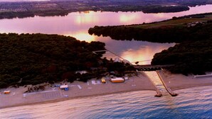 Vista aérea de una zona costera con un puente, playa y terreno boscoso.