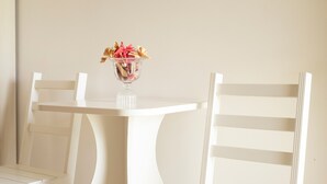 A white table with a glass bowl containing flowers, flanked by white chairs. - Room 'Arancio' with Lake View, Wi-Fi and Air Conditioning (Otranto)