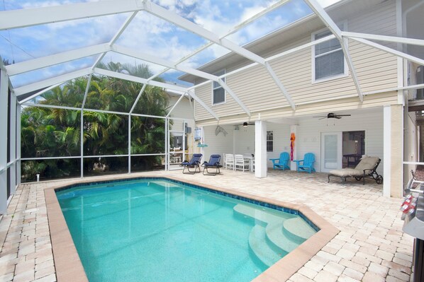A covered swimming pool with lounge chairs and a patio area.