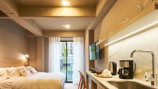 Une chambre d’hôtel comprenant un lit, un bureau avec un lavabo, une télévision et un balcon avec des rideaux.
