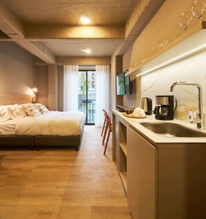 Une chambre d’hôtel comprenant un lit, un bureau avec un lavabo, une télévision et un balcon avec des rideaux.