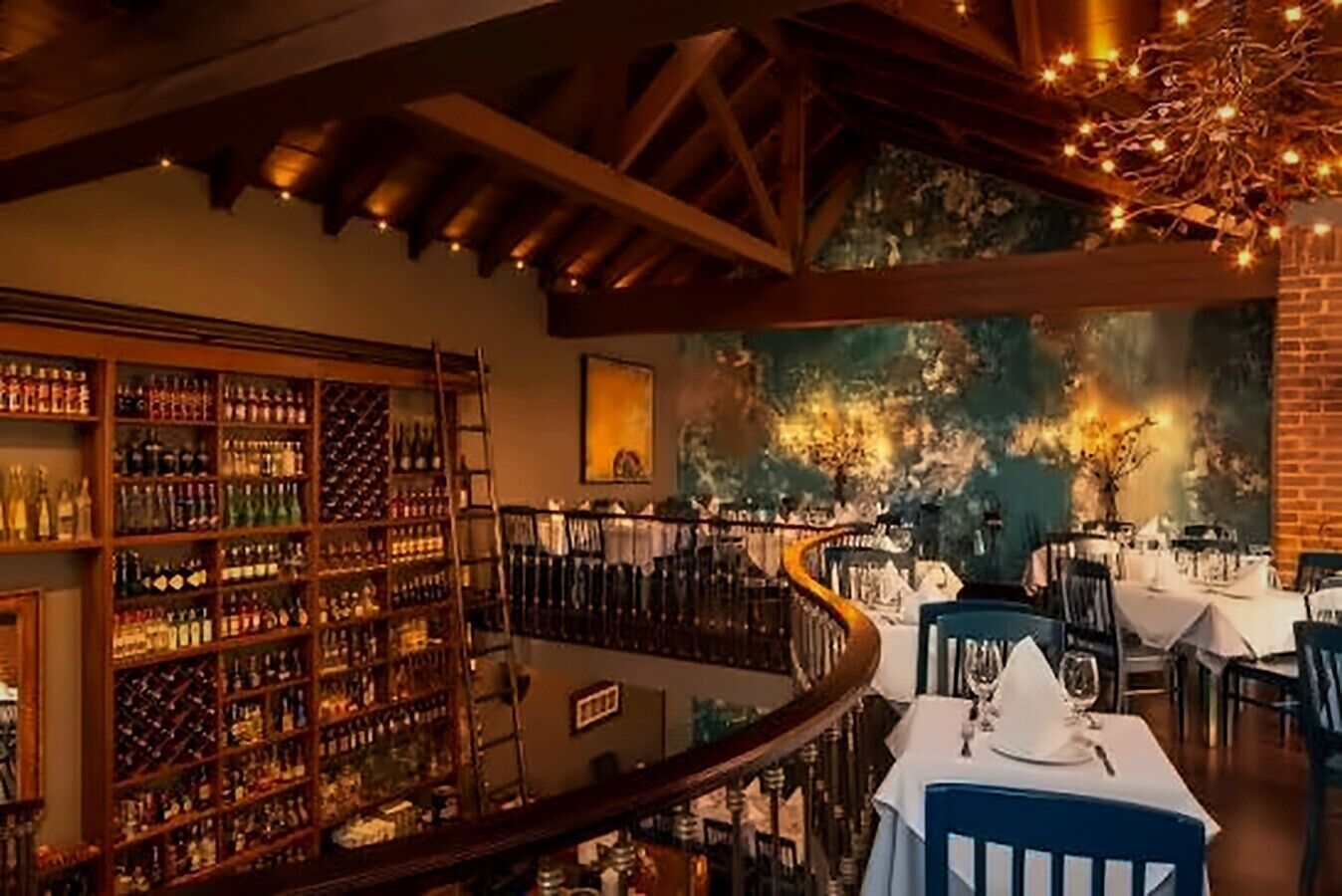 Ein Restaurant mit Weinkeller, Wandgemälde und einem Essbereich mit Tischen und Stühlen.