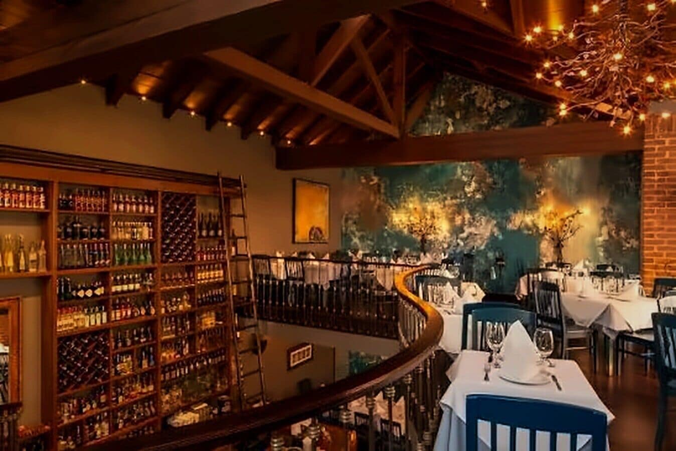 A restaurant with a wine cellar, a mural, and a dining area with tables and chairs.