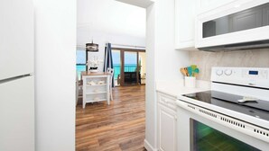 Een moderne keuken met witte kastjes, een inbouwoven en uitzicht naar buiten.