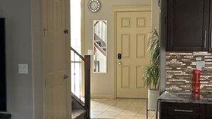 A hallway leading to a staircase with a clock on the wall. - Spacious 4BR Retreat- Perfect for Families & Groups! (Airdrie)
