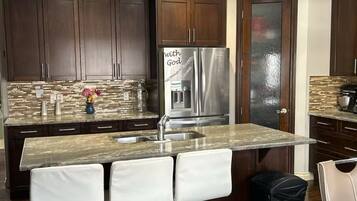 A modern kitchen with dark wood cabinets, a stainless steel refrigerator, and a granite countertop.
