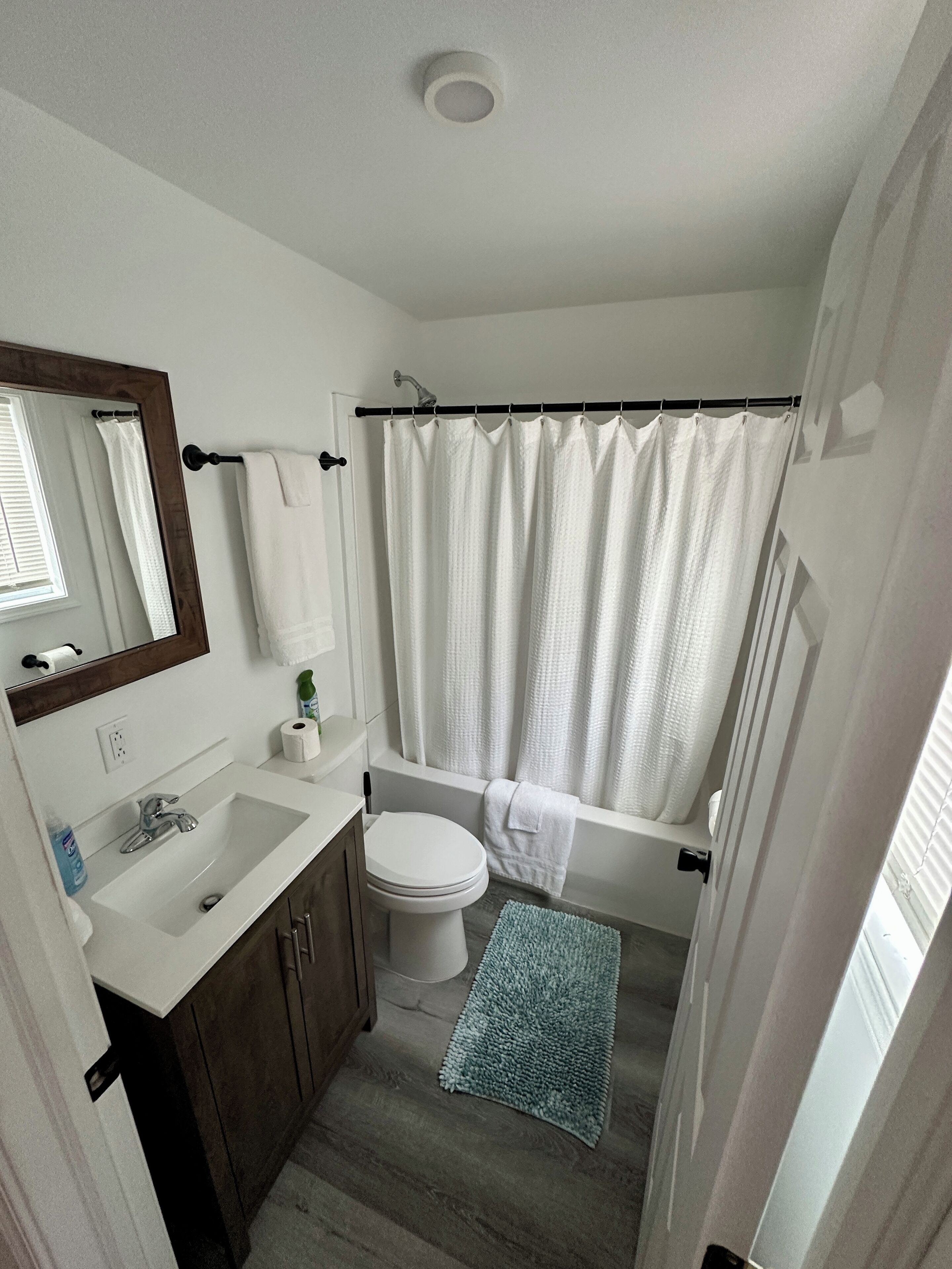 Een badkamer met een wit wastafelmeubel, toilet, bad en douchegordijn.