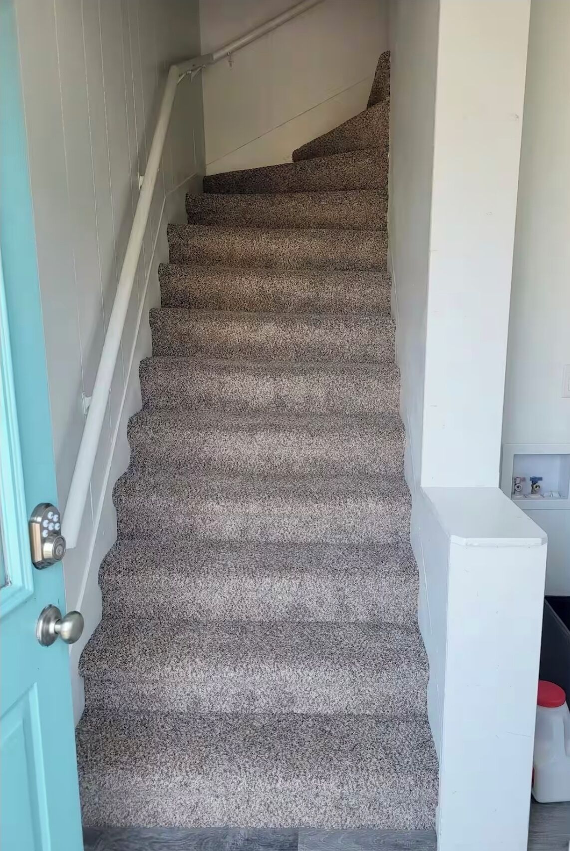 A staircase with carpeted steps leading to a landing.