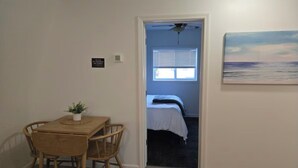 A room with a wooden table and chairs, a bed with a white bedspread, a ceiling fan, and a painting on the wall. - 1-bedroom house in charming Calumet (Calumet)