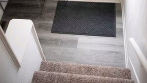 A staircase leading to a teal door with a window, a wooden bench, and a doormat. - 1-bedroom house in charming Calumet (Calumet)