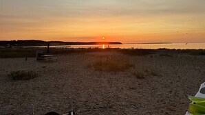 Uma praia com um pôr do sol, uma mesa de piquenique e uma tenda.