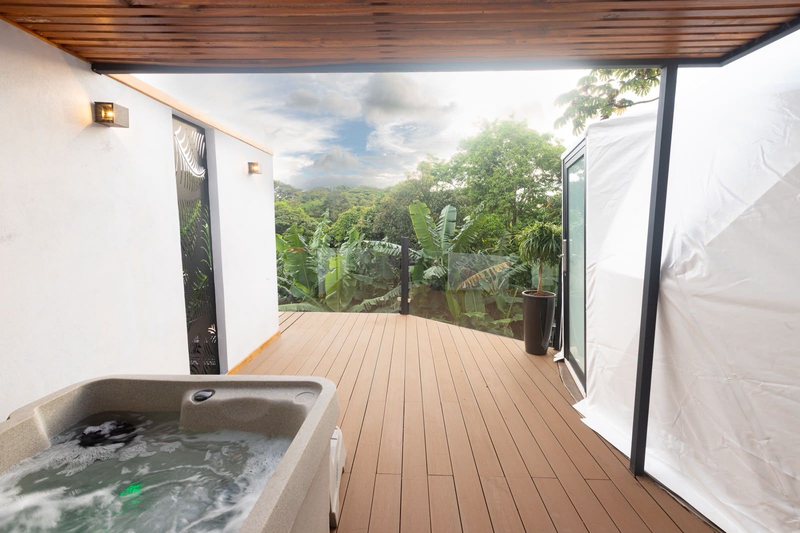 Un jacuzzi en una terraza de madera con vistas a exuberante vegetación.