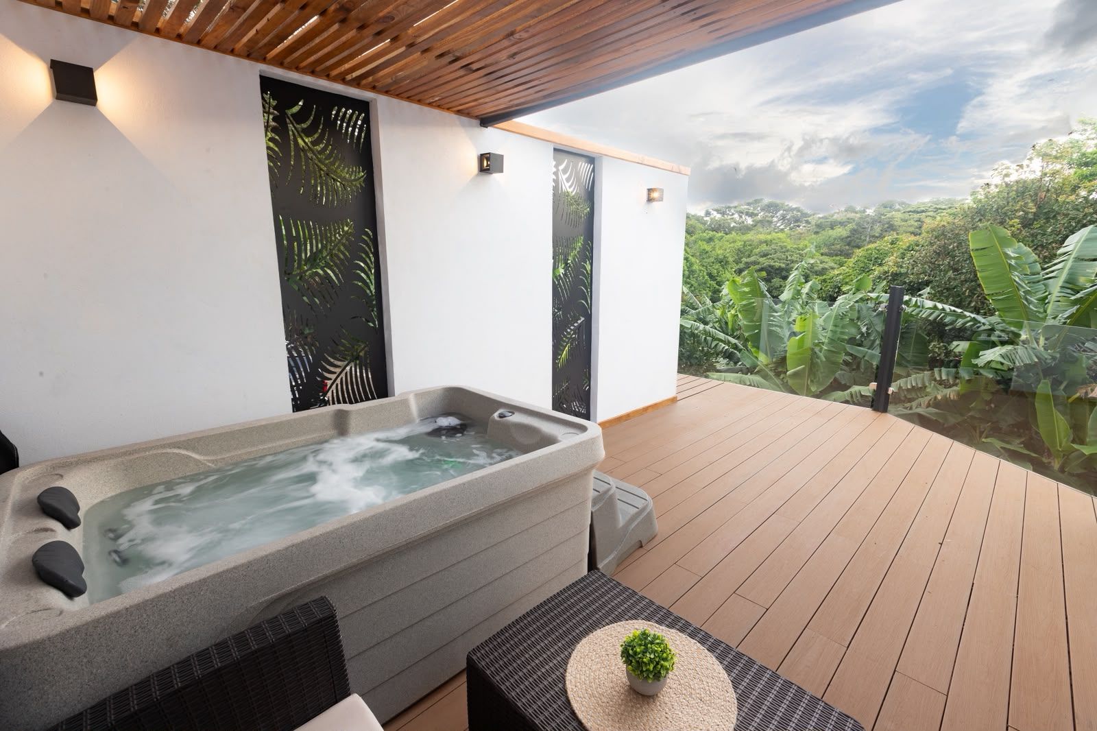 Un jacuzzi en una terraza de madera con vistas a un jardín exuberante.