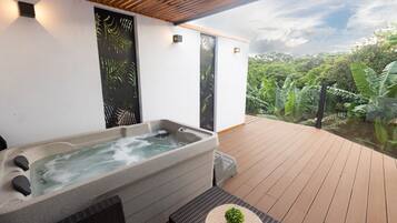 Un jacuzzi en una terraza de madera con vistas a un jardín exuberante.