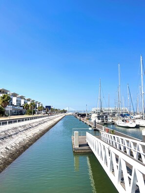 A marina with boats docked, a clear sky, and a stone wall on one side.