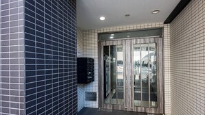 A modern entrance with a glass door, tiled walls, and a mounted intercom. -  SPAZIO 2 Canal Hakata (Fukuoka)