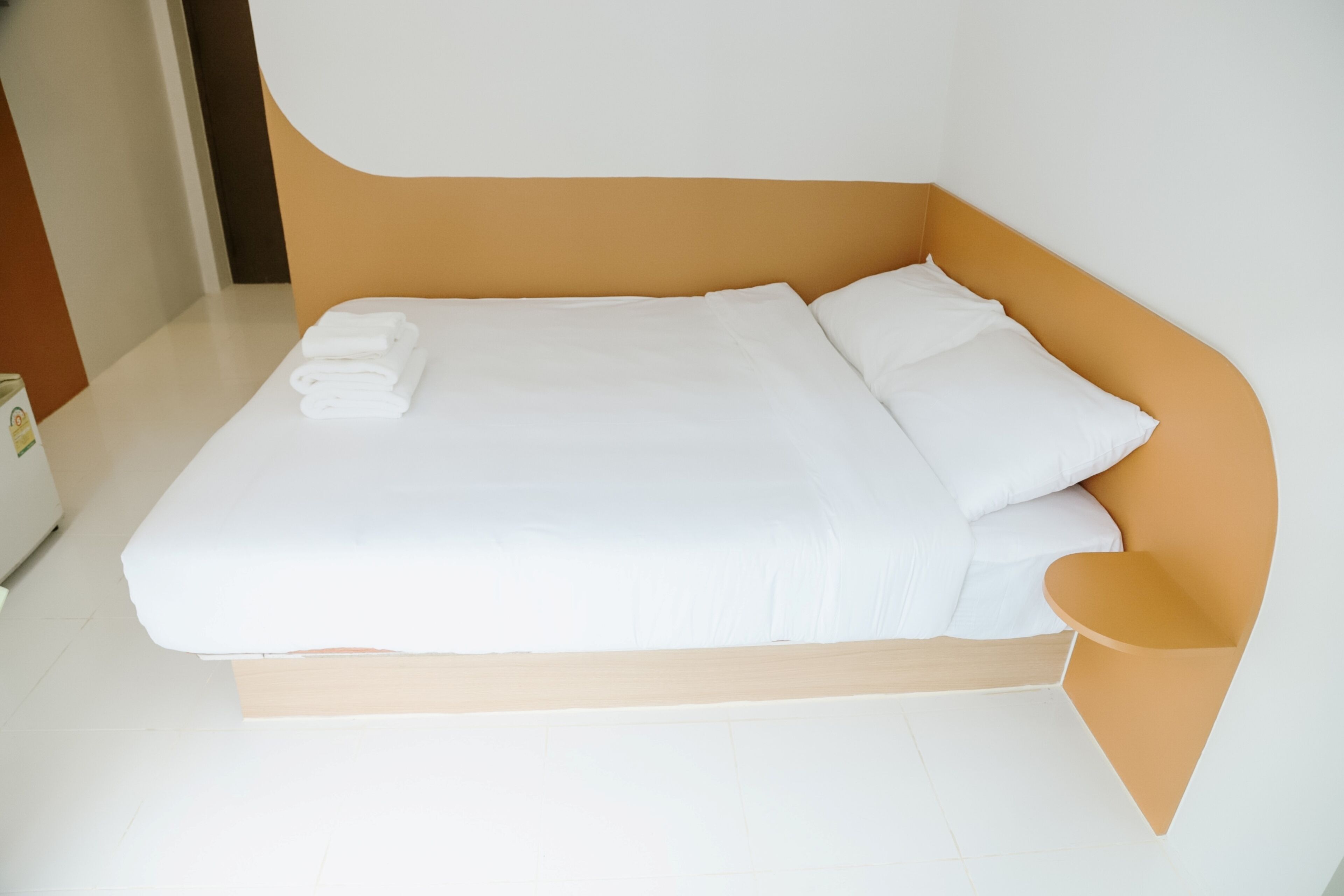 A modern bed with white linens and a wooden headboard.