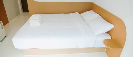 A modern bed with white linens and a wooden headboard.