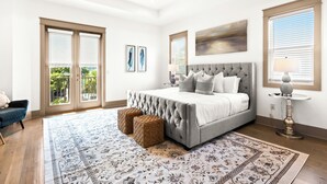 A bedroom with a large bed, a ceiling fan, and a view of the outdoors through the sliding doors.