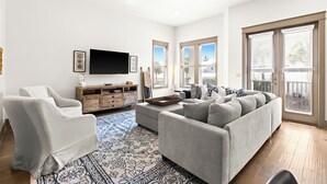 A modern living room with a grey sofa, a white armchair, and a wooden entertainment unit.