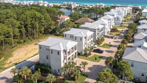A coastal residential area with modern white buildings, a sandy beach, and a clear view of the ocean.