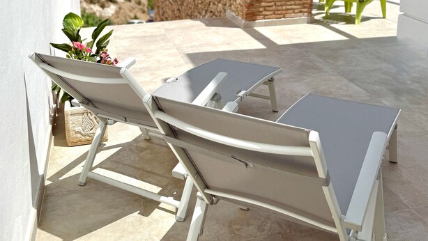 A balcony with two sun loungers, a stone wall, and a view of the sea. - Apartment 'Clementina Garden' with Sea View, Wi-Fi and Air Conditioning (Nerja)