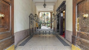 A hallway with a tiled floor, a wrought iron gate, and wooden doors. - Appartamento Puccini - La Vista Apartments (Milan)
