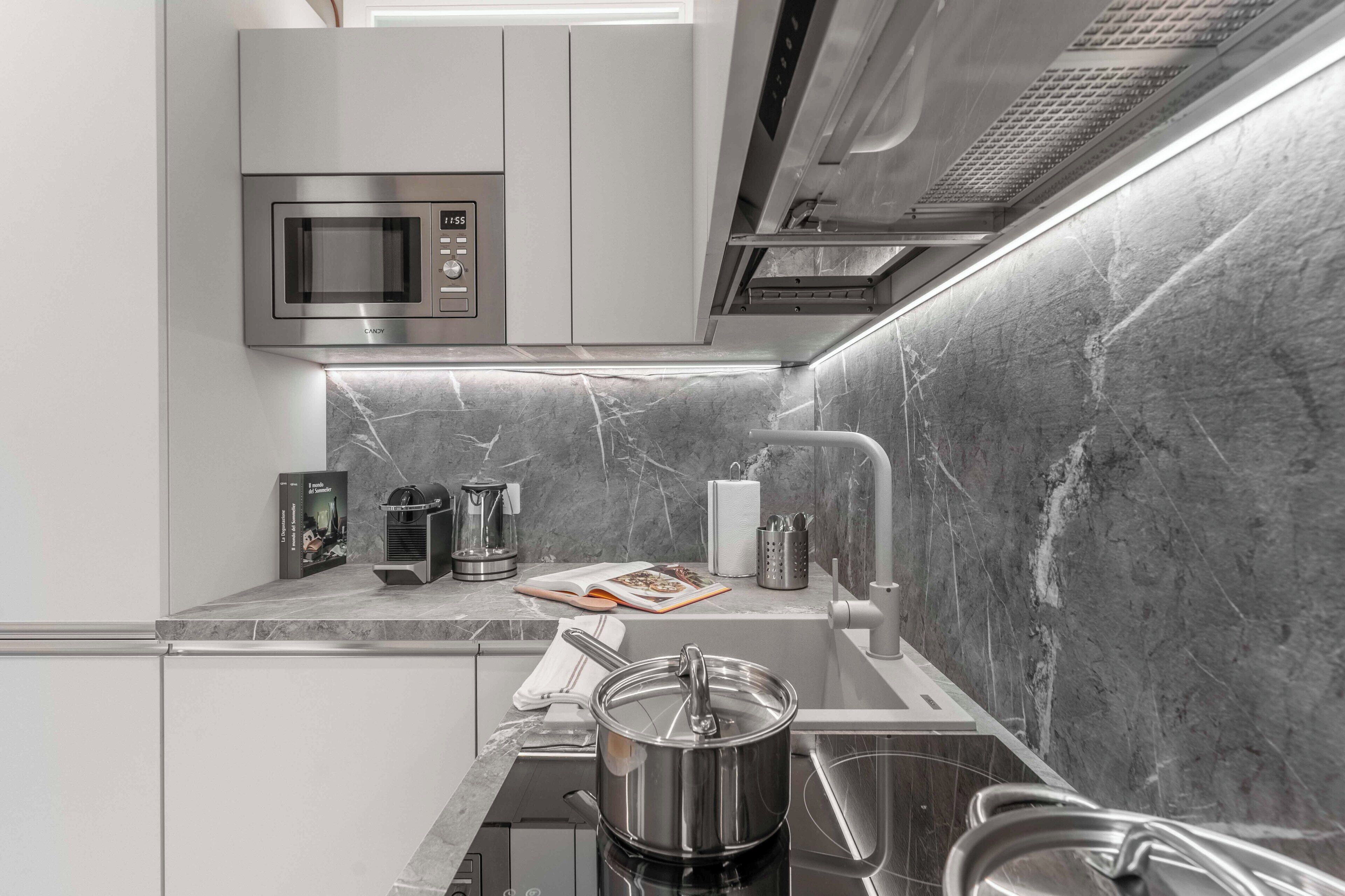 A modern kitchen with a built-in microwave, a coffee maker, and a pot on the counter.
