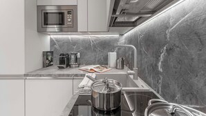 Une cuisine moderne équipée d’un four à micro-ondes encastré, d’une machine à café et d’une casserole posée sur le plan de travail.