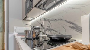 A modern kitchen with a built-in stove, a microwave above it, and a marble backsplash.