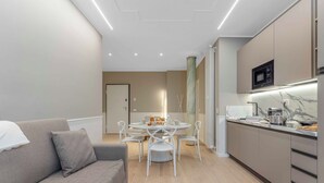 A modern kitchen with a microwave, stove, and dining area with chairs and a table.