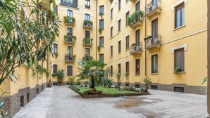A courtyard with yellow buildings, potted plants, and a tiled floor.