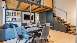 A modern dining area with a high ceiling, exposed beams, and a staircase. - Loftino Bocconi - La Vista Apartments (Milano)
