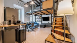 A modern, multi-level living space with a kitchen area, a dining table, a sofa, and a staircase. - Loftino Bocconi - La Vista Apartments (Milano)