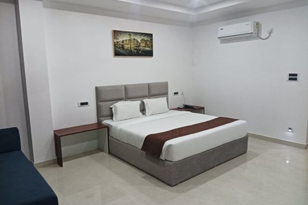 A modern bedroom with a bed, bedside tables, and an air conditioning unit.