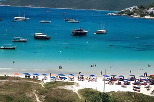 Uma praia com barcos, guarda-sóis e pessoas.
