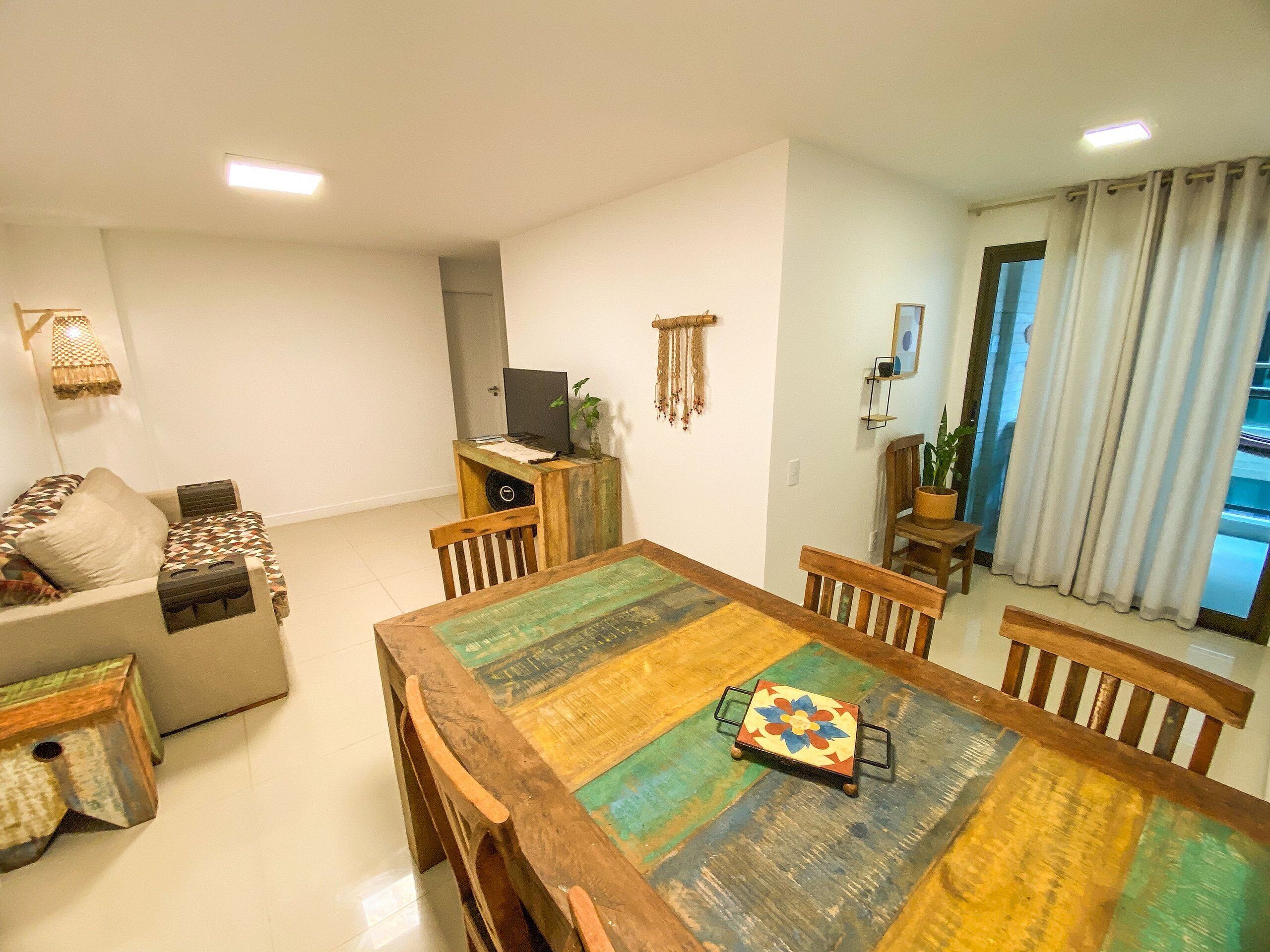 Una sala de estar con una mesa de comedor de madera, un sofá y un mueble para televisión.