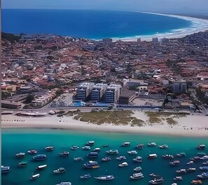 An aerial view of a coastal city with a beach, boats, and buildings.