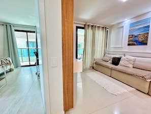 Una sala de estar moderna con un sofá, un cuadro en la pared y vistas a través de un ventanal.
