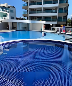 Una piscina con borde de azulejos, rodeada de edificios modernos con balcones.