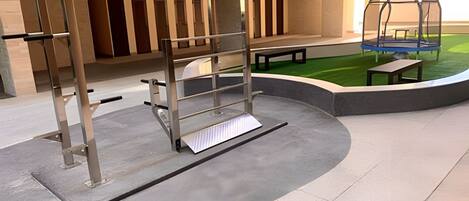 A gym with a pull-up bar, benches, and a small outdoor area with artificial grass.