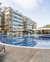 Um hotel moderno com piscina, várias varandas e vista para uma paisagem montanhosa.