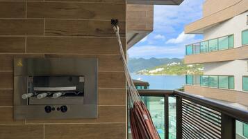 Un balcon doté d’un four en acier inoxydable, une vue sur un paysage montagneux et un bâtiment avec de grandes fenêtres.