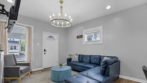 A modern living room with a sectional sofa, a round coffee table, and a chandelier.