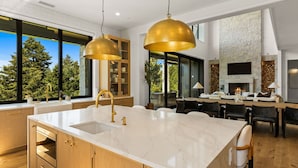 Une cuisine moderne dotée d’un grand îlot central, de meubles en bois et de robinetterie dorée.