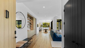 Ein modernes Interieur mit Holzboden, einer Essecke mit Tisch und Stühlen, einem blauen Sofa und einer dunklen Tür.