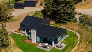 Ein modernes Haus mit einer großen Terrasse, einem Whirlpool und einem gepflegten Rasen.